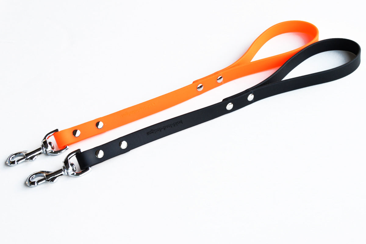 Black and orange Brahma traffic lead dog leashes with metal clasps on a white background
