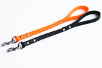 Black and orange Brahma traffic lead dog leashes with metal clasps on a white background
