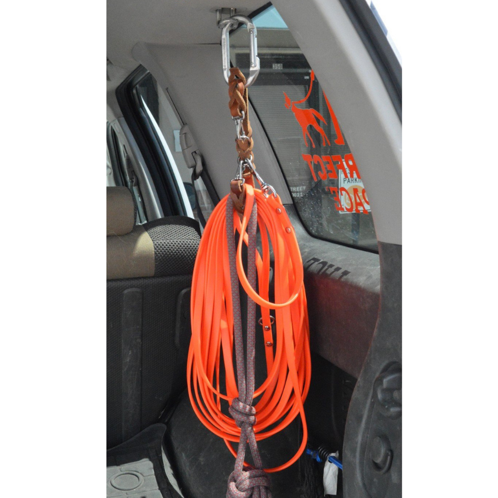 orange longline and rope toy on a tan leather leash caddy, hanging from a hook inside an SUV