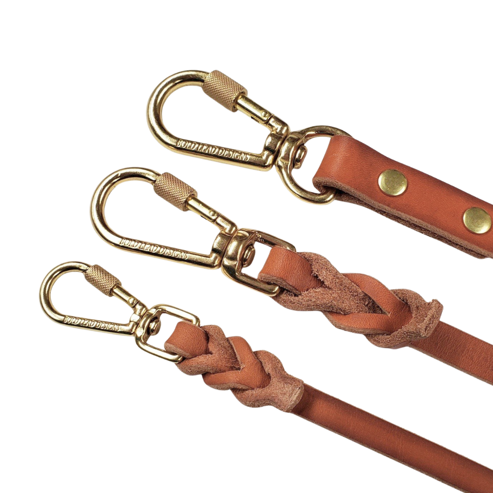 three solid brass locking carabiner swivel snaps on leather dog leashes on a white background
