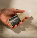 Hand holding a bottle of Eucalyptus Delight body wash with a neutral background