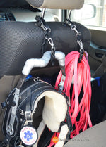 Car interior with leash caddies hanging from the back of the headrest, one cady is holding a service dog harness, the other is holding a pink longline