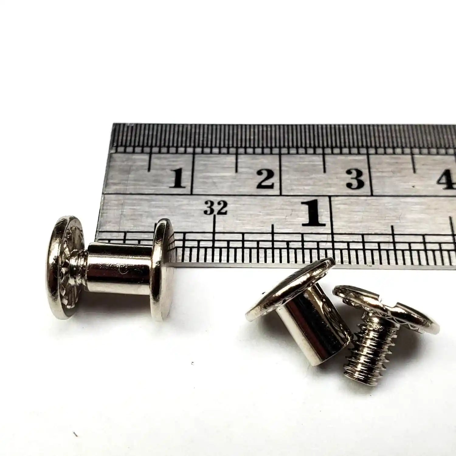 1/4 inch Chicago screws with a ruler for scale on a white background