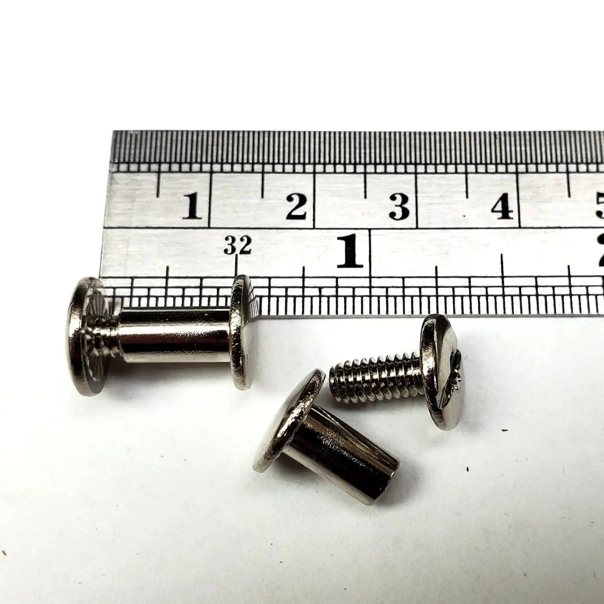 3/8 inch Chicago screws with a ruler for scale on a white background